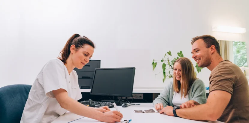 A couple consulting with a female doctor in a bright office, discussing IVF treatment preparations.