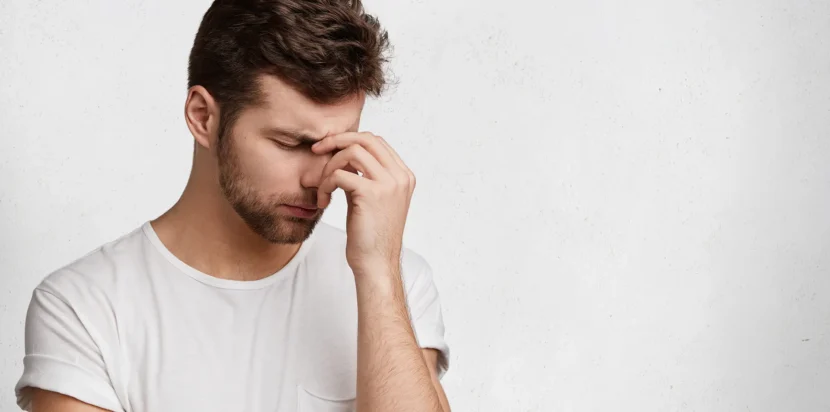 A concerned man holding his head, representing the emotional impact of low sperm count and male infertility.